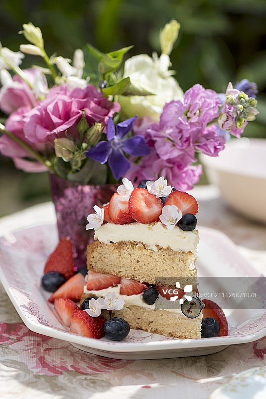 一块带浆果的维多利亚海绵蛋糕放在户外的桌子上图片素材