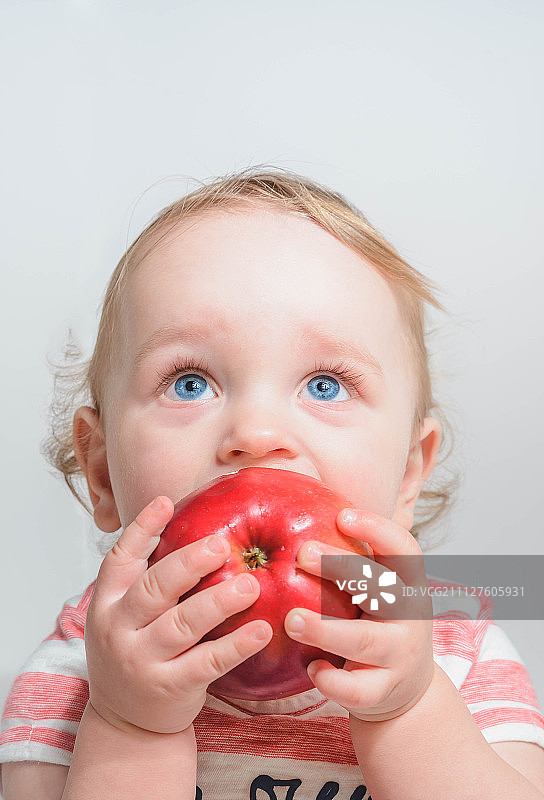 孩子拿着一个苹果吃图片素材