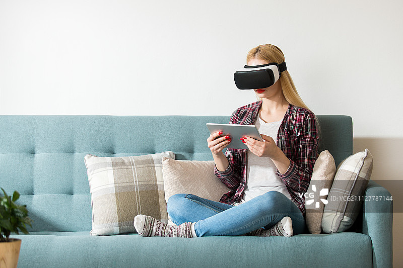 美女戴着虚拟现实眼镜躺在沙发上。虚拟现实耳机……图片素材