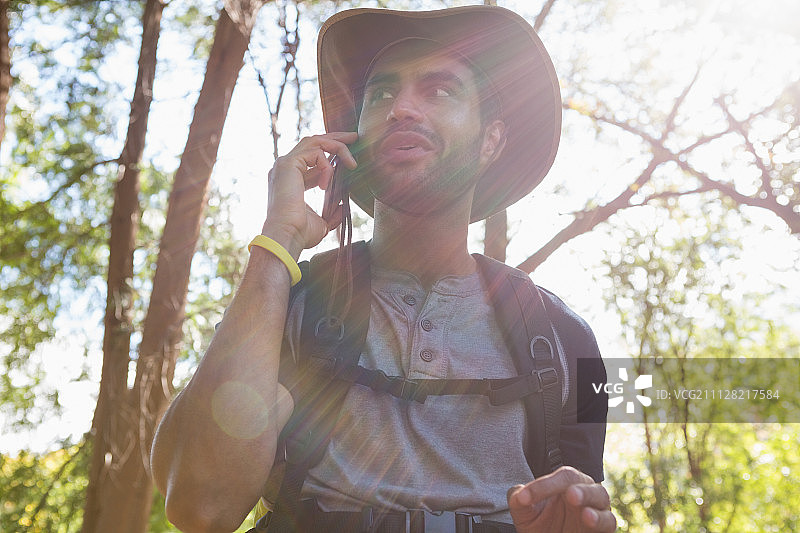 在一个阳光明媚的日子里，一个微笑的男人在森林里用手机聊天图片素材
