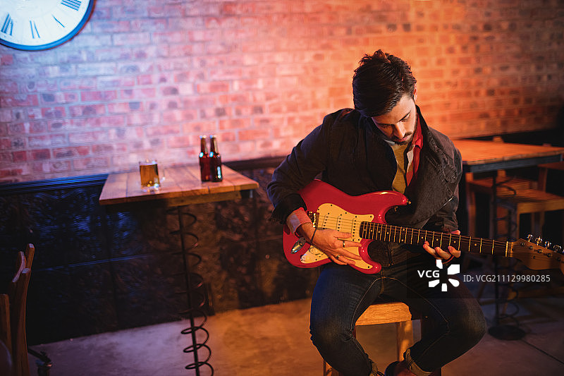 一个年轻人在酒吧里弹吉他图片素材