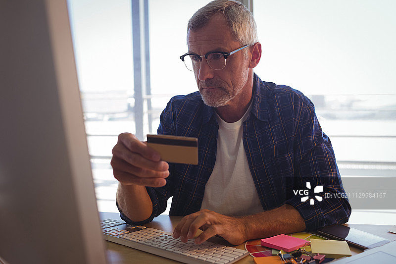 严肃的生意人在办公室的办公桌上用信用卡在网上购物图片素材