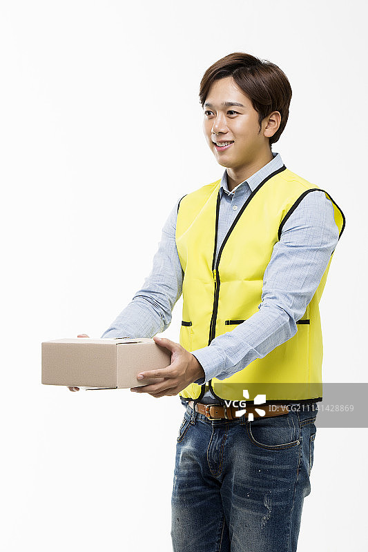 年轻的亚洲男子在黄色背心给一个纸板盒图片素材