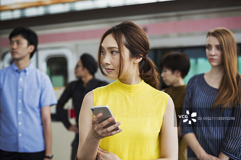 一小群人站在地铁站台上，东京通勤者。图片素材