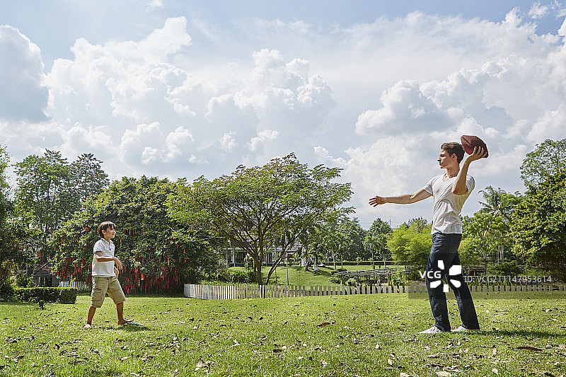 一个男人和一个男孩在公园里玩橄榄球图片素材