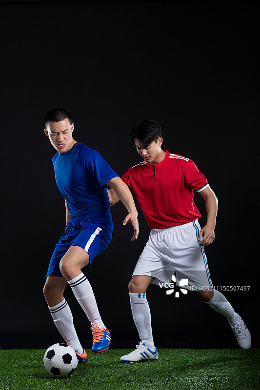 两名年轻足球运动员在草地上踢足球比赛图片素材