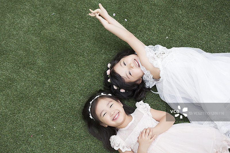小女孩打扮成天使躺在草地上图片素材