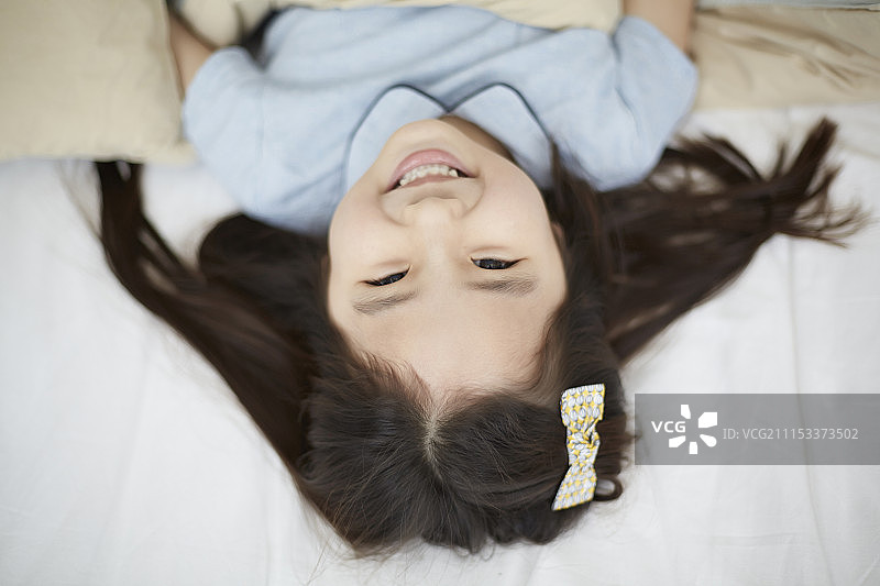 小女孩躺在床上微笑的照片图片素材