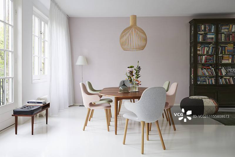 白色地板上的餐桌周围有彩色装饰的椅子图片素材