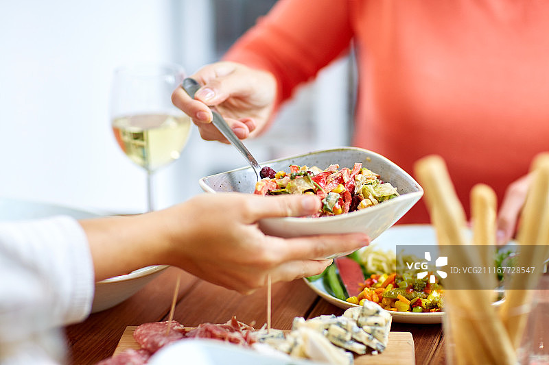 食物、饮食和休闲概念——人们用沙拉吃晚餐。人们在餐桌上和食物一起吃沙拉图片素材