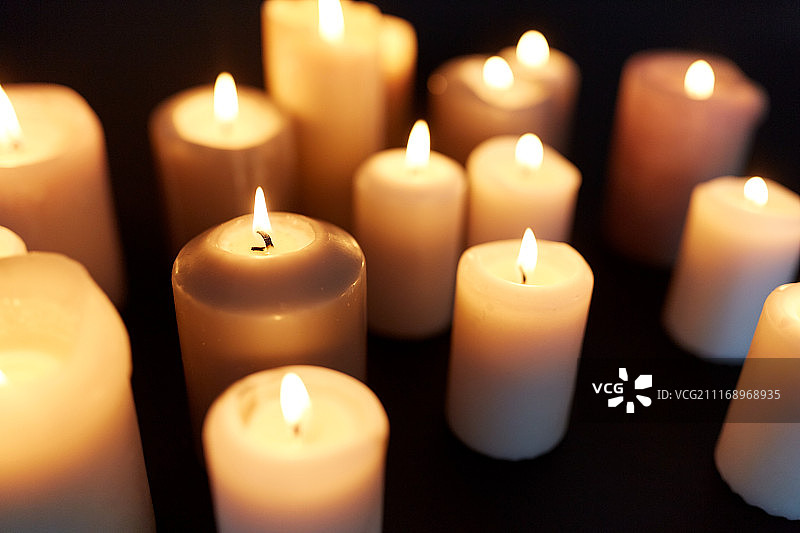 悼念和纪念的概念-蜡烛燃烧在黑暗的黑色背景。黑色背景下的蜡烛在黑暗中燃烧图片素材