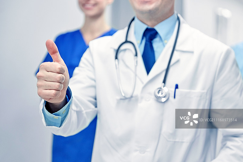 专业，人，保健，手势和医学概念-近距离高兴的医生或医生在医院走廊显示大拇指。医生在医院显示拇指的特写图片素材