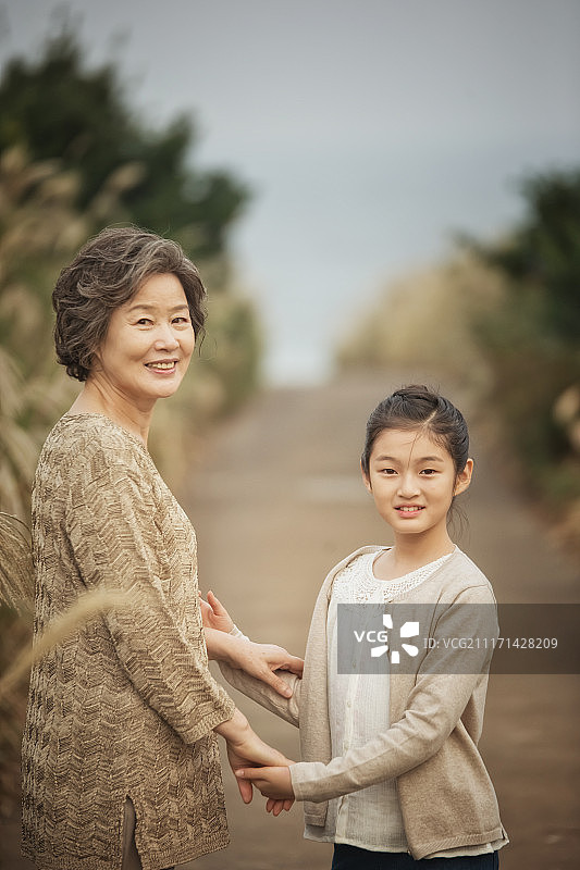 祖母和孙女手牵着手站在济州岛的银草旁图片素材