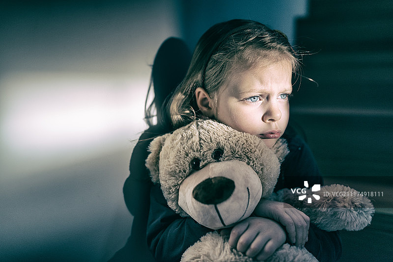 悲伤的小女孩拥抱她的泰迪熊-感到孤独图片素材