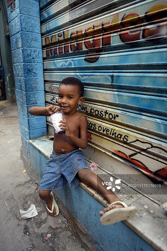 小男孩在贫民窟吃冰淇淋，Jacarezinho favela，里约热内卢de Janeiro，里约热内卢de Janeiro State, Brazil, South America ***重要:巴西禁止出版***图片素材