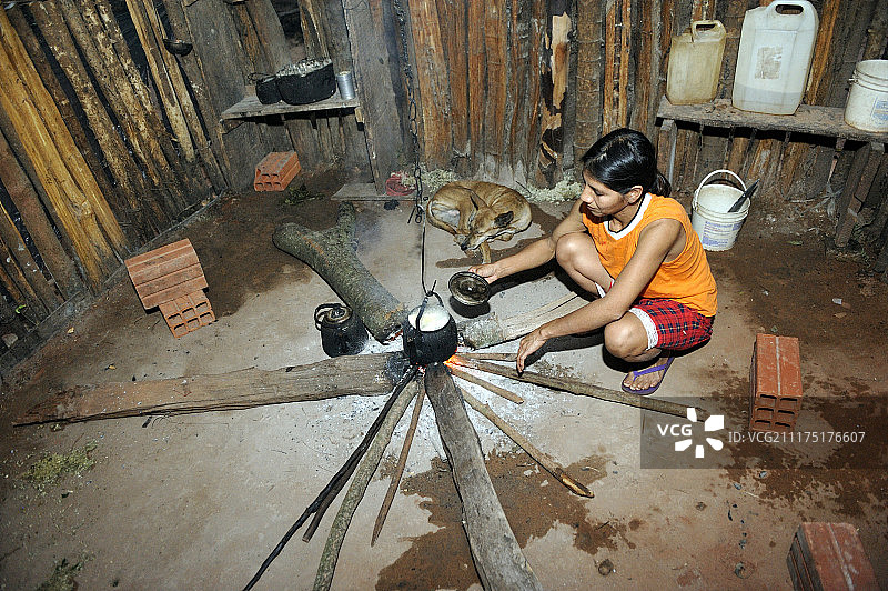 南美巴拉圭卡瓜苏省坎皮托姆比亚瓜拉尼印第安人社区，一名34岁的妇女在简易厨房的明火上用锅煮木薯图片素材