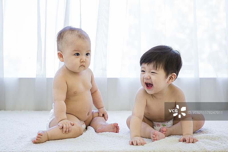 两个可爱宝宝的照片。婴儿穿着尿布在白色的卧室。136图片素材