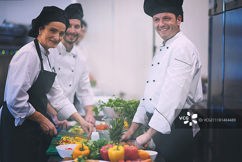 专业团队厨师和厨师在繁忙的酒店或餐厅厨房准备饭菜。团队厨师和厨师准备饭菜图片素材