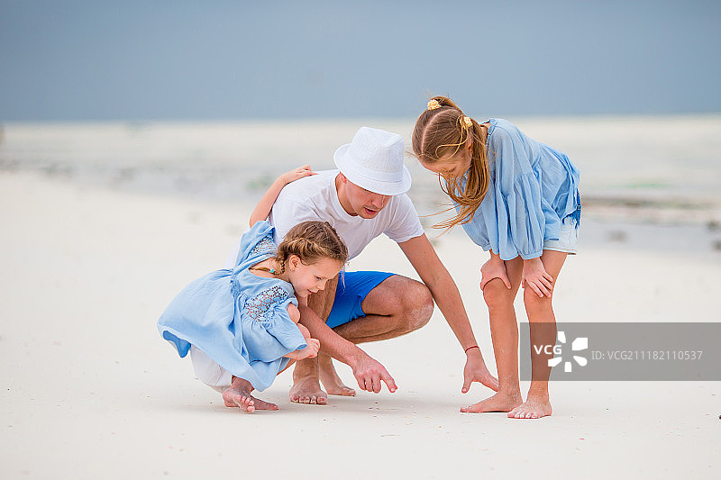 父亲和两个女儿在海滩上图片素材