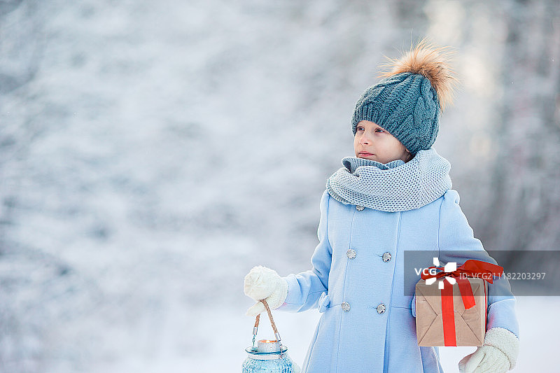 女孩拿着圣诞礼物在冬天的风景图片素材