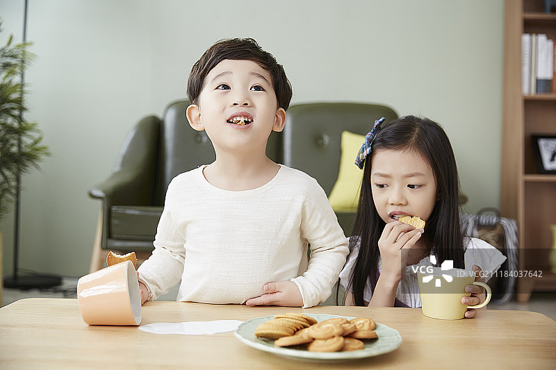 小男孩和小女孩吃糖果，把牛奶洒在桌子上图片素材