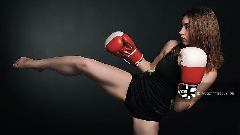 漂亮的年轻女人在一个红色拳击手套在黑色的背景图片素材
