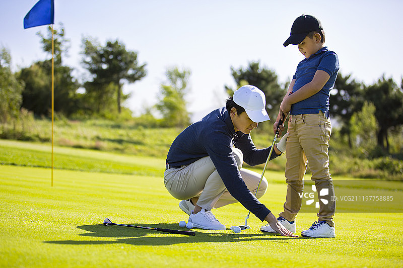 青年教练教小男孩在户外打高尔夫球图片素材