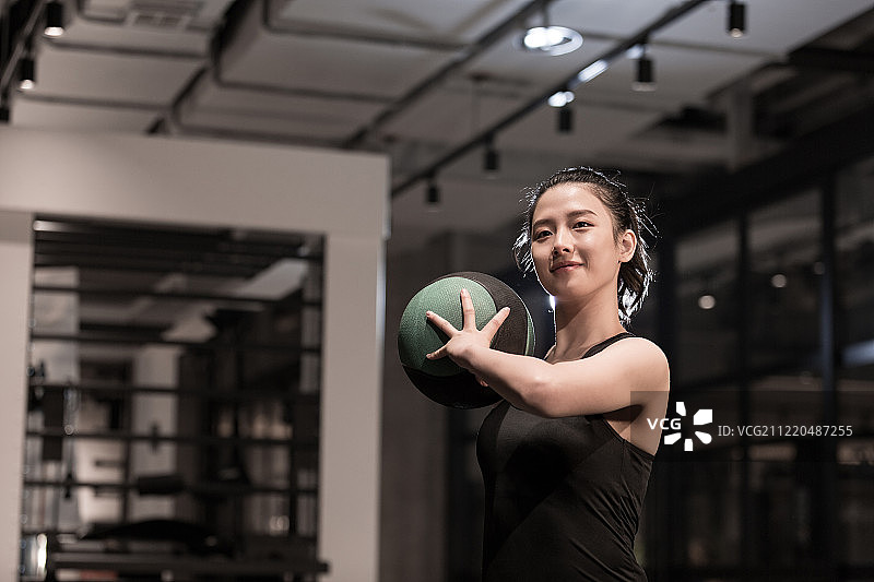 青年女子在健身房拿着实心球做健身运动图片素材