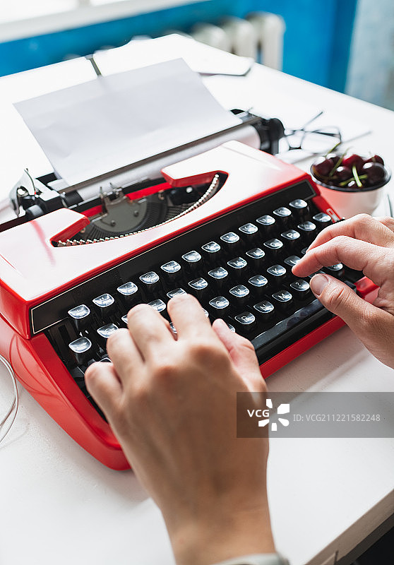 用亮红色老式打字机工作的女人图片素材
