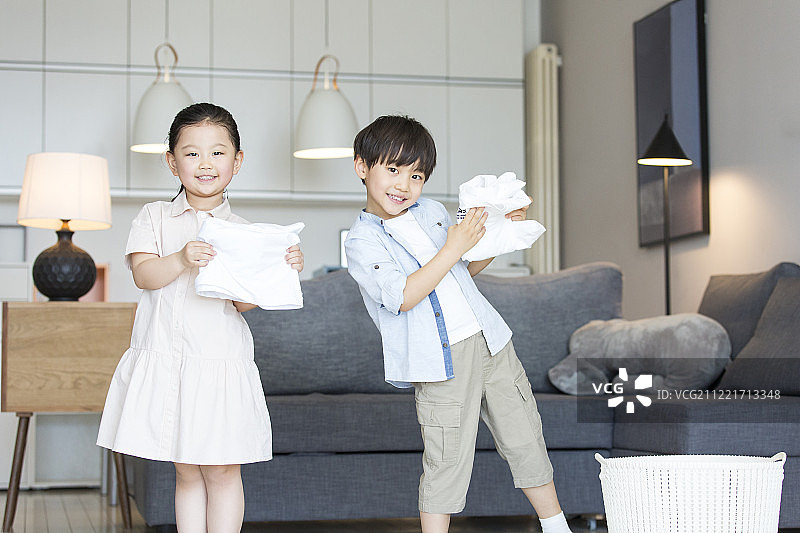 两个孩子在客厅叠衣服做家务图片素材