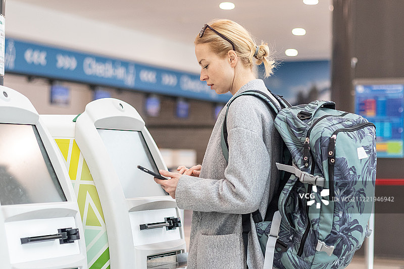 随便一个白人女人在机场使用智能手机应用程序和值机……图片素材
