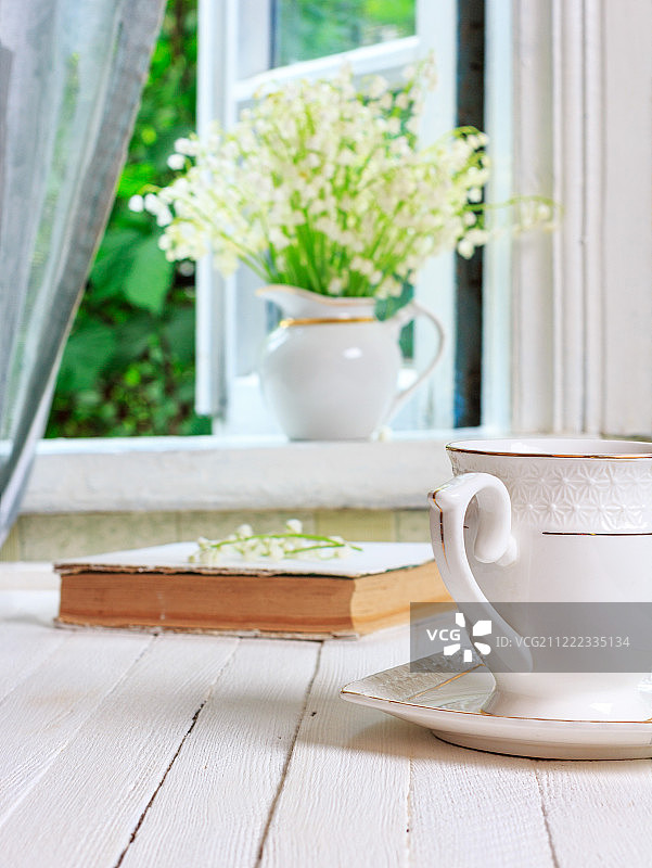 一杯茶或咖啡和一本书在一个白色的木制古董复古桌子和一束图片素材