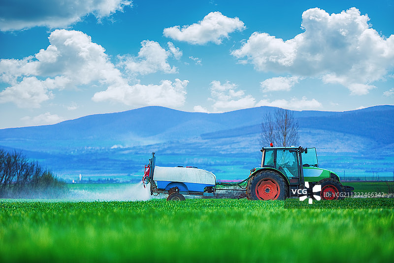 农用拖拉机在田间犁地和喷洒图片素材