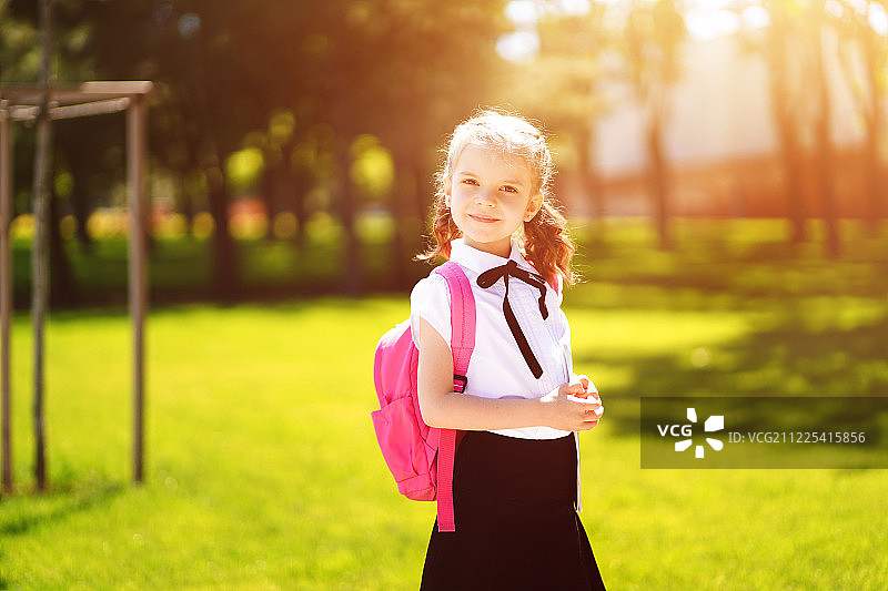 美丽的小女孩背着背包在公园里散步准备回学校图片素材