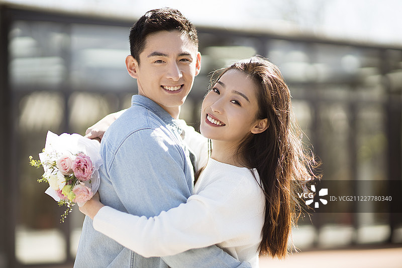 年轻女子手拿鲜花拥抱男朋友图片素材