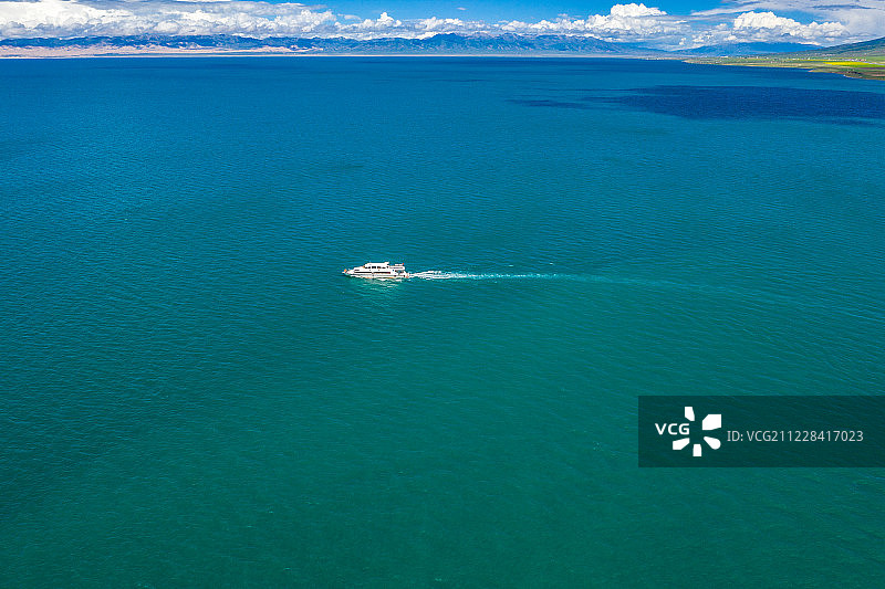 航拍蓝天白云下的夏季平静的青海湖的湖面上驶过的一艘游轮图片素材