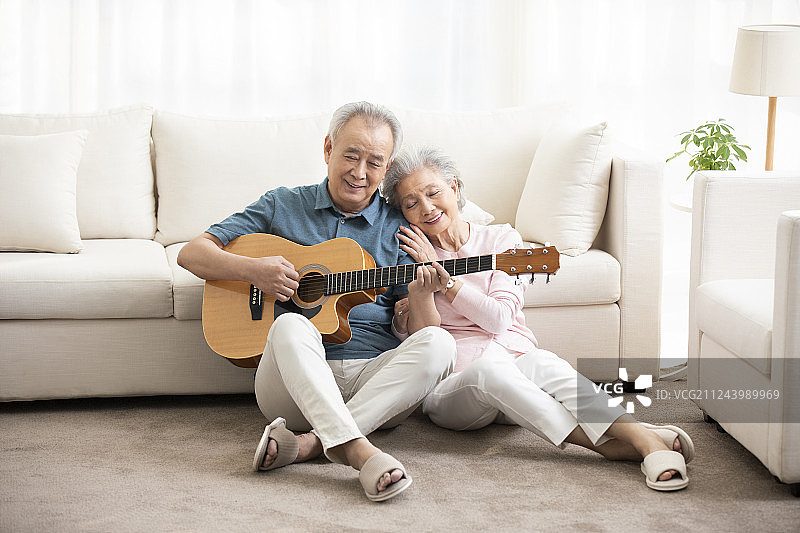 快乐的老年夫妇在客厅弹吉他图片素材