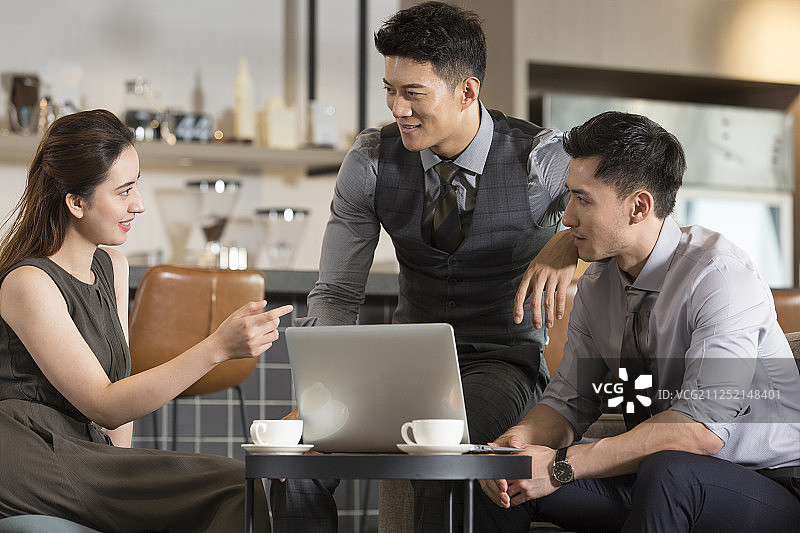 三个成功商务青年男女在咖啡馆使用笔记本电脑沟通工作图片素材