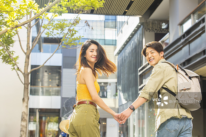 青年情侣在户外商业街手牵手浪漫逛街旅行图片素材