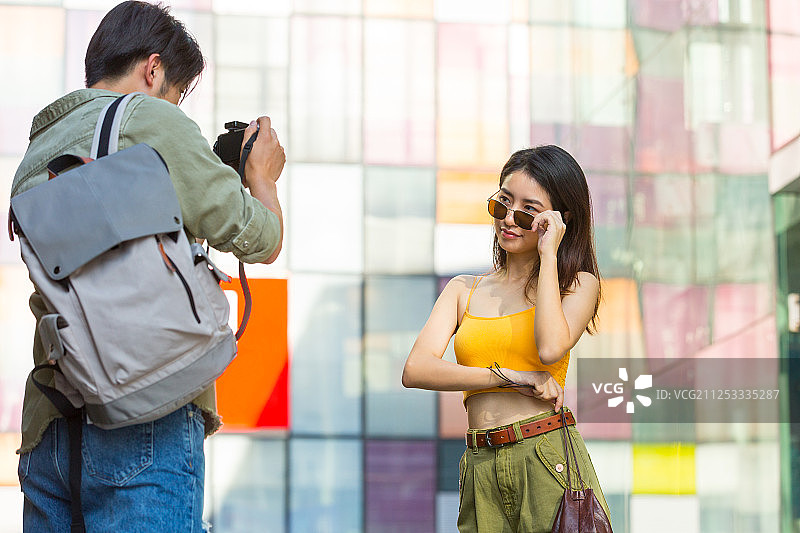 年轻情侣在户外商业街逛街旅游拍照图片素材
