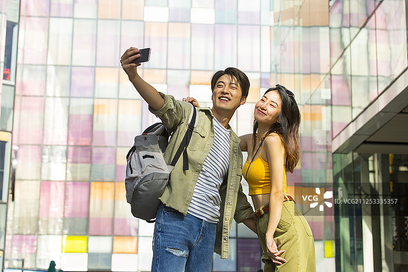 浪漫情侣在户外步行街逛街旅行拿手机自拍嬉戏图片素材
