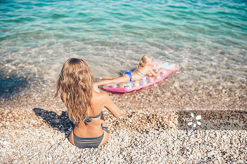 年轻女子享受太阳日光浴在完美的绿松石海洋图片素材