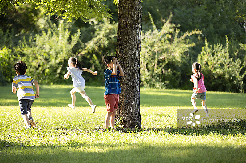 快乐的儿童在草地上玩捉迷藏图片素材