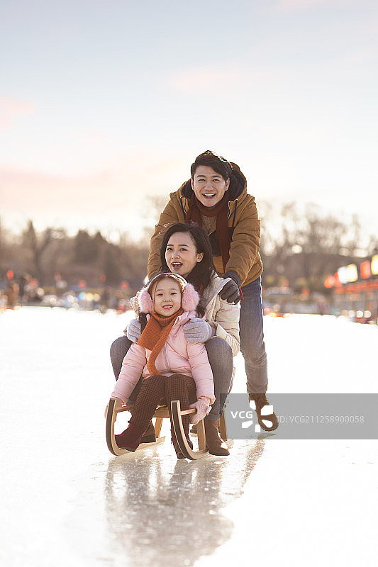 年轻家庭在户外玩雪橇图片素材