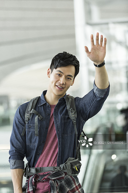 背旅行包的青年男子在机场挥手图片素材