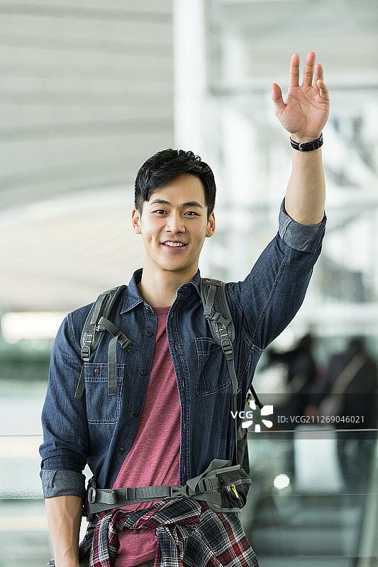 背旅行包的青年男子在机场招手图片素材