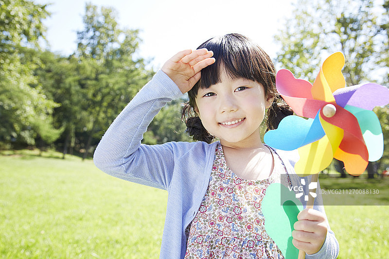 小女孩手持纸风车在公园里的照片图片素材