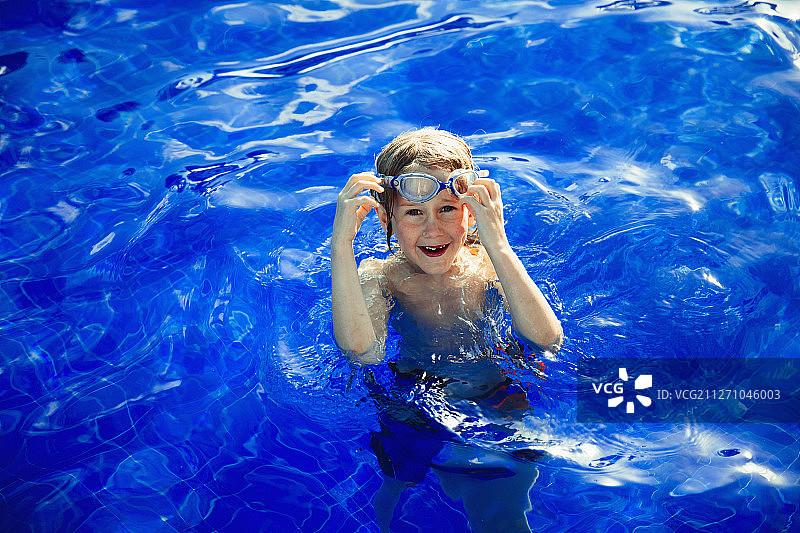 肖像快乐的男孩游泳在阳光蓝色游泳书图片素材