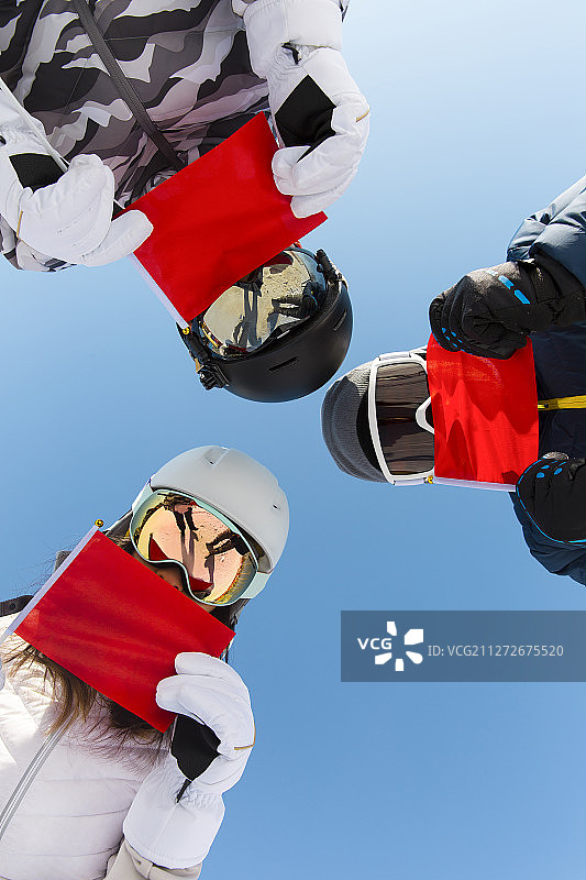 三个青年男女拿着红旗在滑雪场为冬奥会加油喝彩图片素材