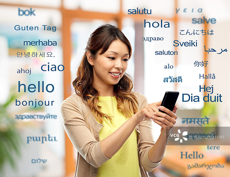 教育、交流和翻译概念——快乐的亚洲女性使用智能手机而不是不同的外语问候词。快乐的亚洲女人使用智能手机图片素材